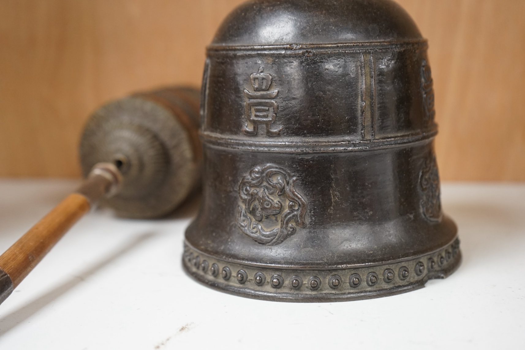 A late 19th/early 20th century Tibetan prayer wheel, with silver mounted bamboo handle, and a Southeast Asian bronze bell, largest 28cm wide. Condition - fair